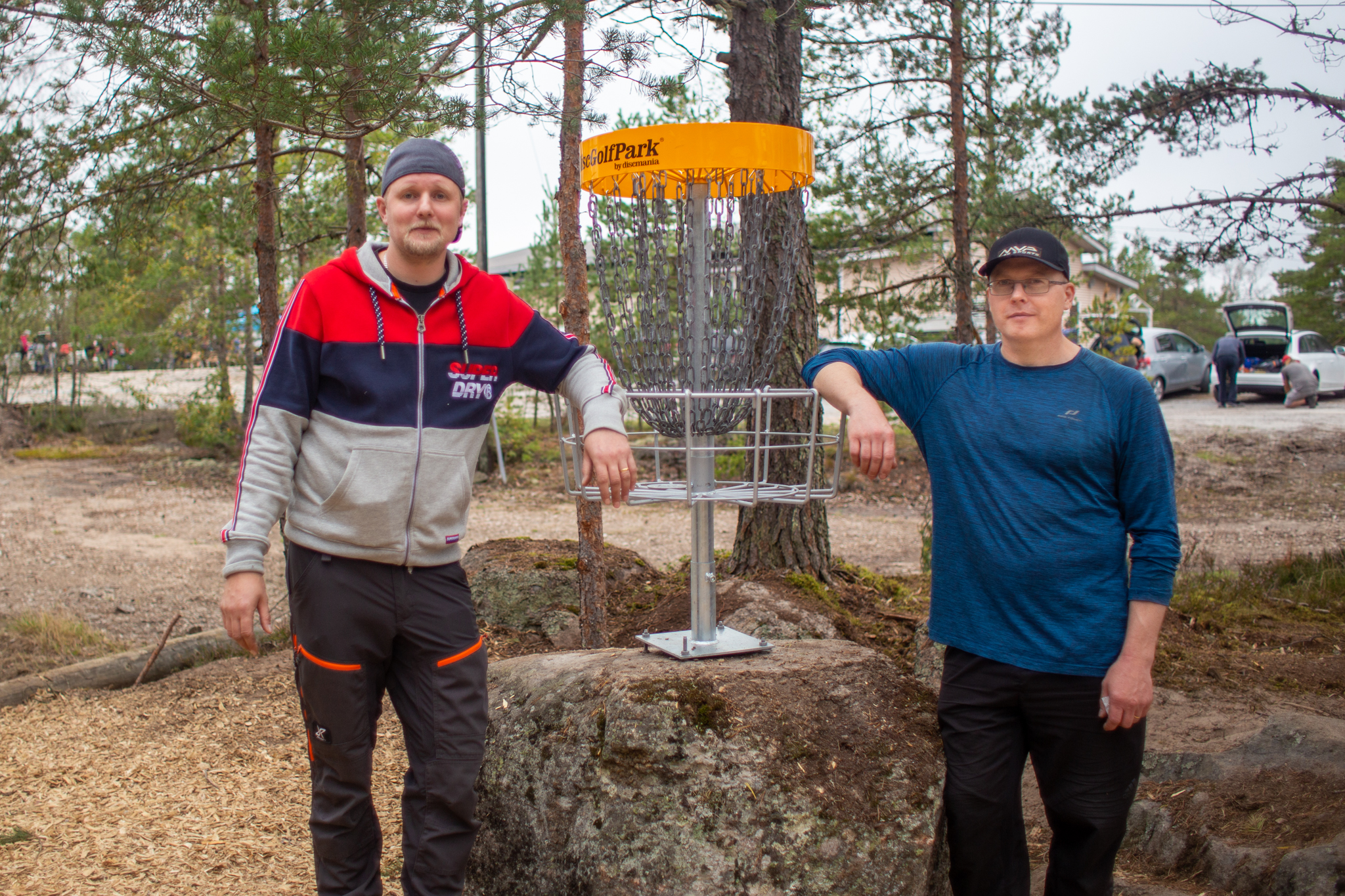 Ville Aerila ja Pekka Siivonen Kirikallion frisbeegolfradalla nojaamassa koriin.